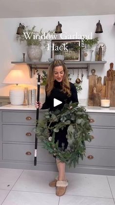 a woman standing in front of a kitchen counter holding a wreath