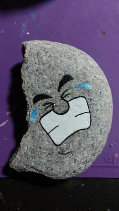 a rock with a face drawn on it sitting next to a purple wall and floor