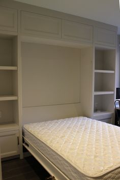 a mattress is in the middle of a room with built - in bookcases