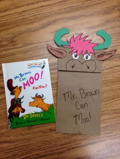 a brown paper bag with a pink hair on it next to a children's book