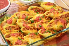 a glass casserole dish filled with stuffed shells covered in meat and sauces