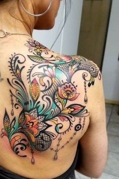 the back of a woman's shoulder with colorful flowers and leaves on her chest