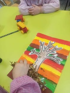 a child is painting a tree on a piece of paper with legos in the background