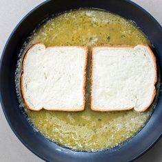 two pieces of bread sit on top of some soup in a pan with broth