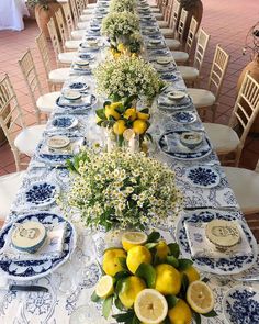 a long table is set with blue and white china, lemons, baby's breath