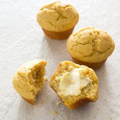 three muffins with icing sitting on top of white paper