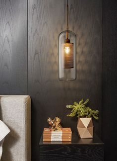 a lamp hanging from the side of a wall next to a couch and table with books on it