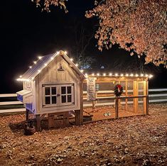 a chicken coop is lit up with christmas lights and garlands on the fence around it