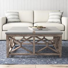 a white couch sitting next to a wooden table on top of a blue area rug