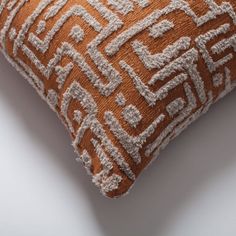 an orange and white decorative pillow on a white surface