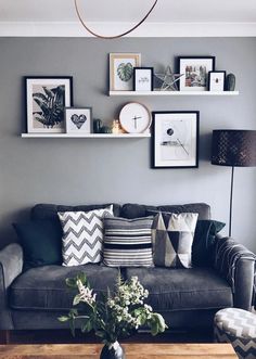 a living room with grey walls and pictures on the wall above the couch, along with a wooden coffee table