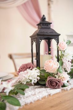 a table topped with a candle and flowers on top of a lace covered table cloth