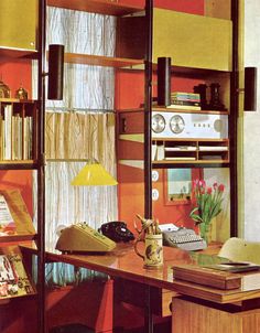 a room with a desk, bookshelf and various items on the shelves in it