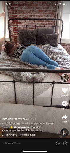 a woman laying on top of a bed next to a brick wall in a bedroom