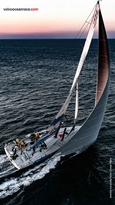 a sailboat is sailing in the open ocean at sunset or dawn with people on it