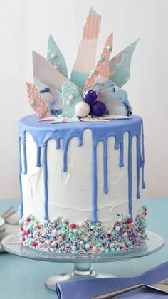 a cake with blue icing and sprinkles on it sitting on a table