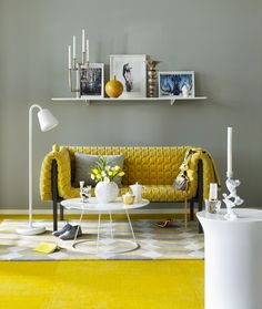 a living room with yellow furniture and pictures on the wall above it's shelves