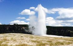 a large geyser spewing water into the air from a hill side