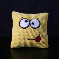 a crocheted pillow with eyes and tongue sticking out from it's side