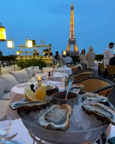 an outdoor dining area with tables and chairs covered in oysters, lemon wedges and wine glasses