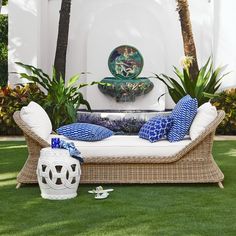 a white couch sitting on top of a lush green field next to a palm tree