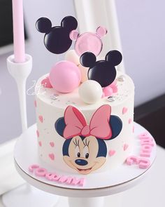 a minnie mouse cake with pink and white decorations on it's top, sitting on a table