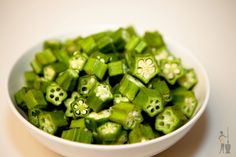 a white bowl filled with green vegetables on top of a table