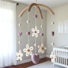 a baby crib mobile with flowers and hearts hanging from it's sides in a nursery room