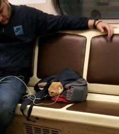 a man sitting on a train with headphones and a backpack next to him,