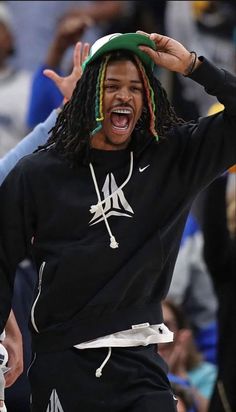 a man with dreadlocks and a green hat on his head is screaming at the crowd