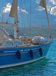 a blue sailboat floating on top of the ocean