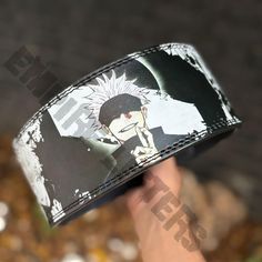 a hand holding up a black and white anime wristband