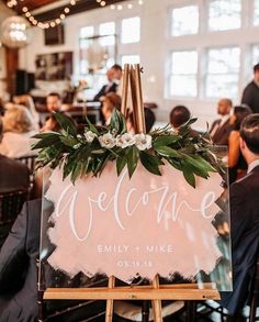 a welcome sign sitting on top of a easel in front of a group of people