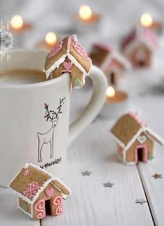 some cookies are in the shape of houses next to a cup of hot chocolate and marshmallows