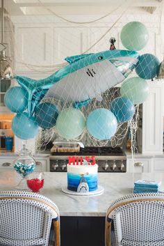 a birthday cake sitting on top of a table next to balloons and an air plane