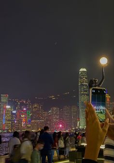 many people are standing around looking at the city lights