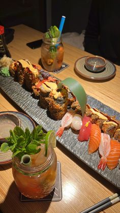 sushi platter on a table with chopsticks and drinks