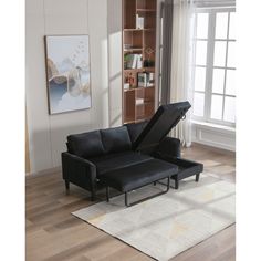 a living room with a couch, ottoman and bookshelf on the floor in front of a window