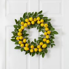 a wreath made out of lemons hangs on the front door's white paneling