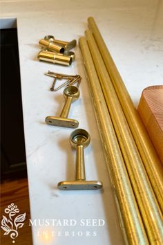 several brass handles are lined up on a marble counter top, and there is a wooden block next to them