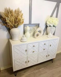 a white dresser topped with lots of vases and flowers