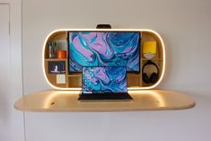 a laptop computer sitting on top of a wooden shelf in front of a wall mounted mirror