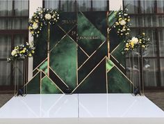 a white table topped with flowers next to a green and gold wall mounted display case