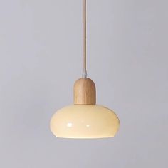 a white light hanging from a wooden ceiling fixture on a gray wall in a room