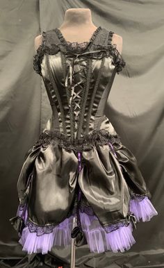 Steampunk outfit. Gothic outfit Black Vintage gothic outfit Stunning gothic 2 piece costume outfit consisting of:...  * 1.The Corset is a black satin. It has peplums and the sides are black Lycra . It has wide lace straps.It has a corseted front and a zip in the back. It has trimmings . This is a size S Uk 8/10 chest 34/36 inch M chest 36/38inch  L chest 38/40 inch   * 2 the full mini skirt is fully lined skirt . It is black satin with lilac purple net and is layered and has lining. * It has pre