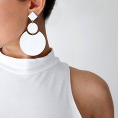 a woman wearing white earrings and a white top