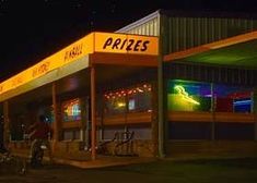 an image of a store at night with bikes parked in the front and on the sidewalk