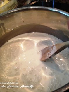 a person stirring milk in a pot with a wooden spoon