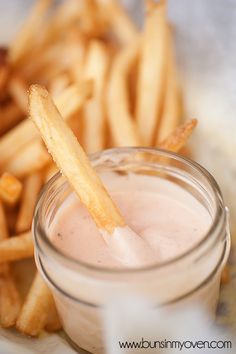 a glass jar filled with liquid next to french fries