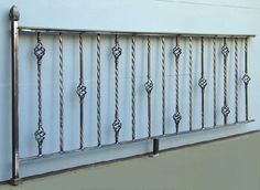 a metal fence with decorative designs on it's sides against a white building wall